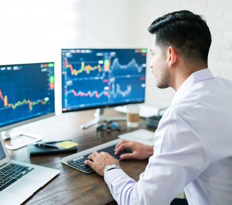 Professional trader analyzing complex market charts across multiple high-resolution displays